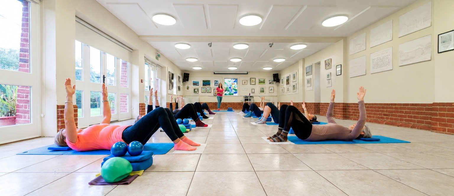 Page Pilates class exercising together in the village hall